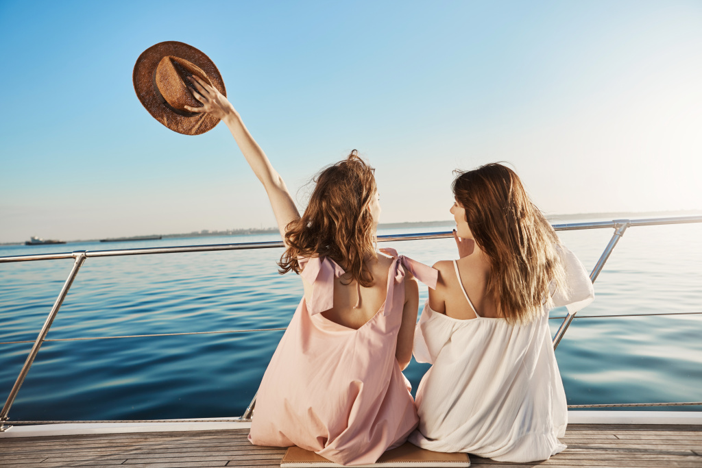 back-portrait-two-female-friends-sitting-boat-waving-with-hat-while-talking-enjoying-looking-seaside-sisters-finally-took-vacation-visit-their-mom-who-lives-italy.jpg